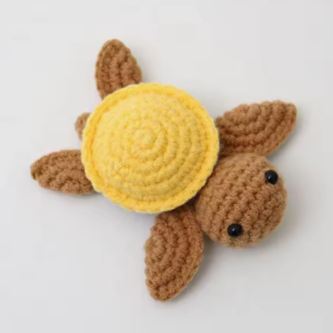 Crocheted turtle toy with a yellow shell on a white background